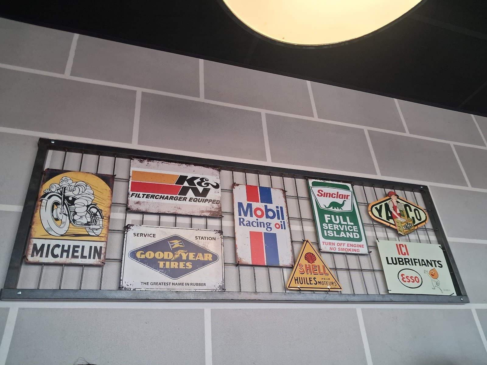 Plaques émaillées vintage Michelin, Mobil et Shell sur les murs du Paddock