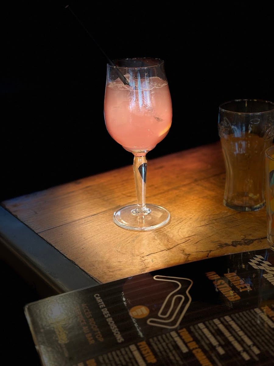 Cocktail rosé posé sur la carte des boissons du Paddock, ambiance tamisée